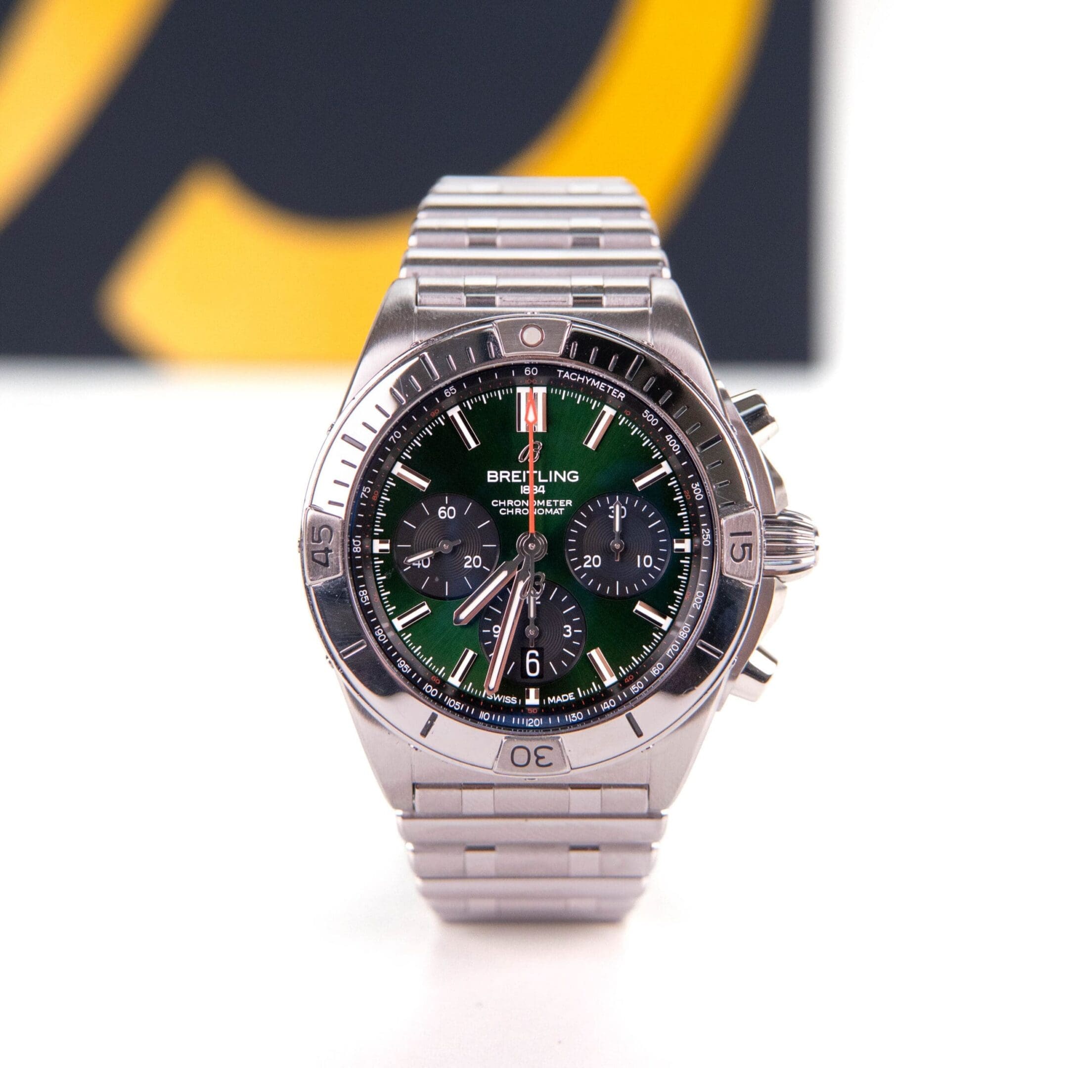 Silver watch with green dial and chronograph.