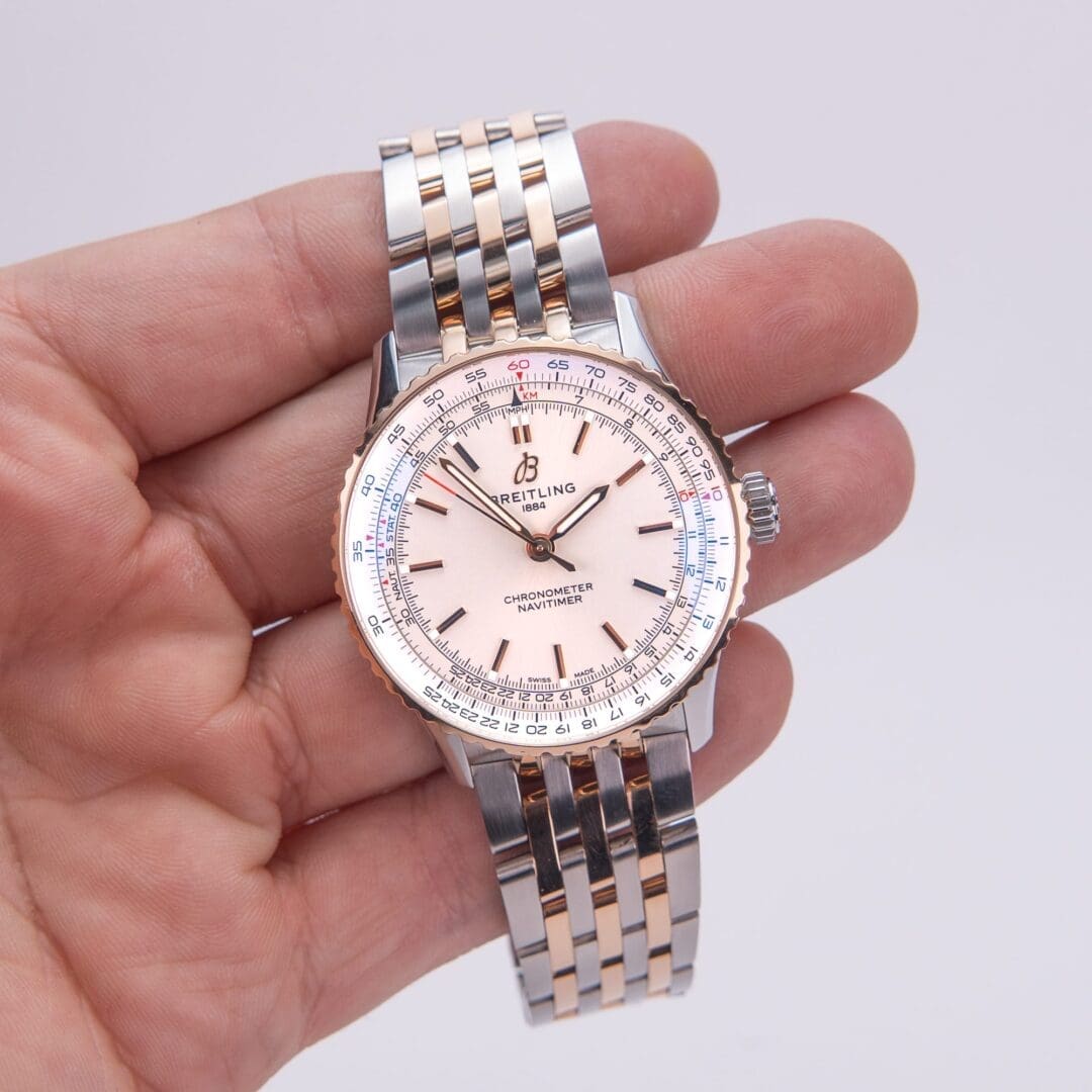 Hand holding a luxury wristwatch with bracelet.