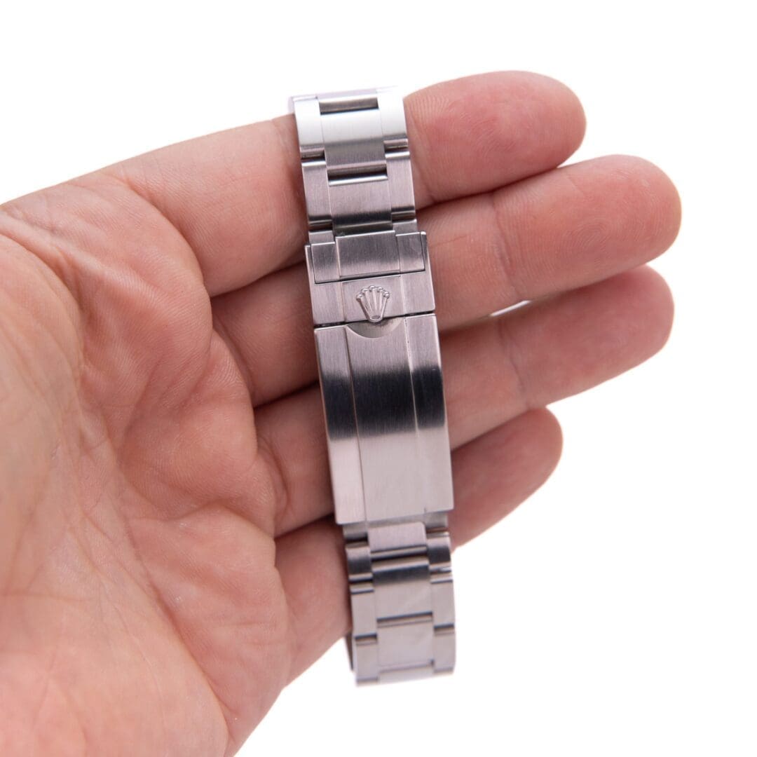 Hand holding a silver metal watch bracelet.
