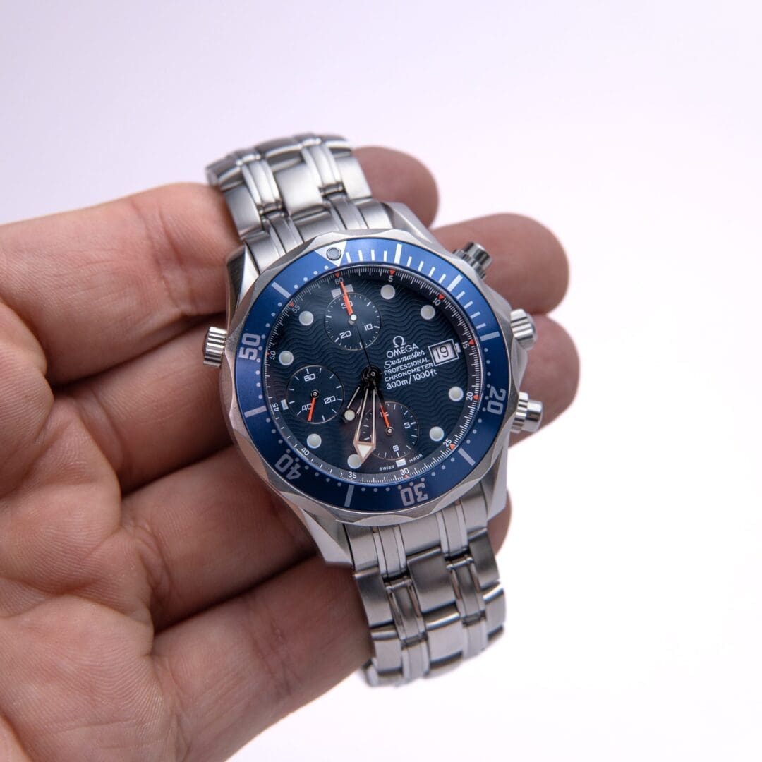 Silver wristwatch with blue dial in hand.