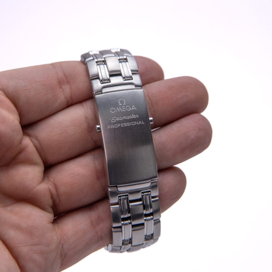 Hand holding Omega Seamaster watch bracelet.