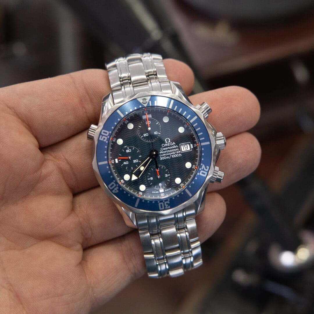 Hand holding a luxury watch with bracelet.