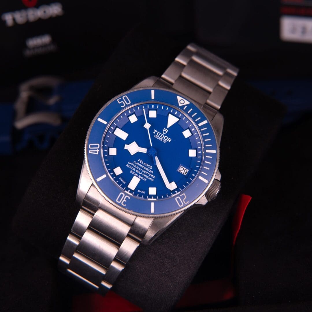 Blue Tudor wristwatch with stainless steel bracelet.