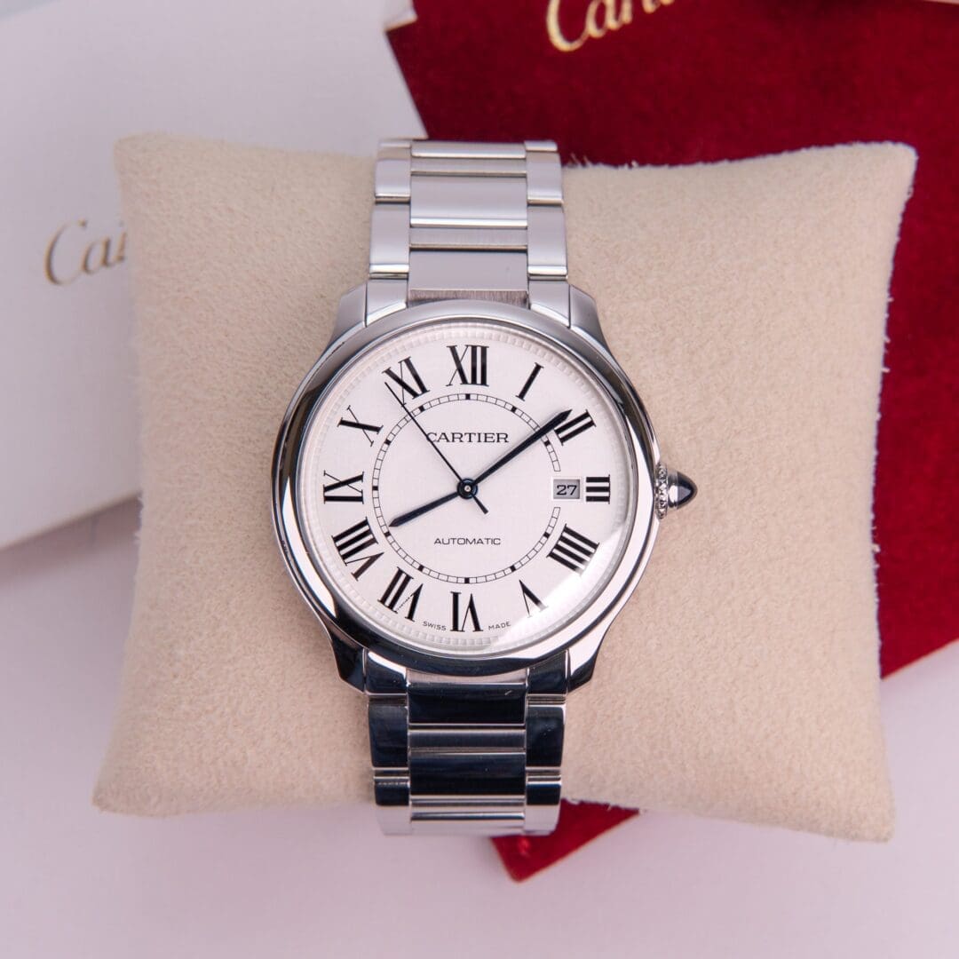 Silver Cartier watch on a cushion.