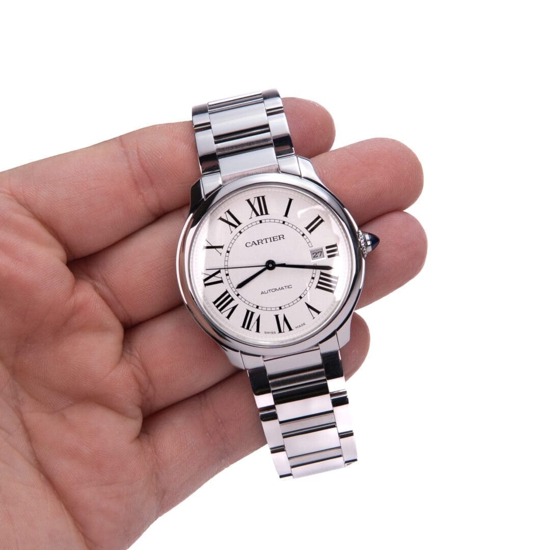 Hand holding a silver wristwatch with numerals.