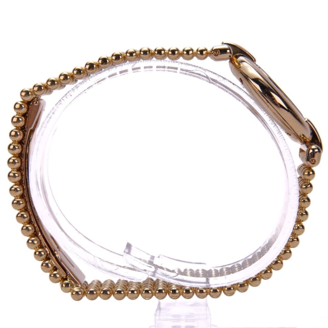 Gold beaded bracelet on display stand.