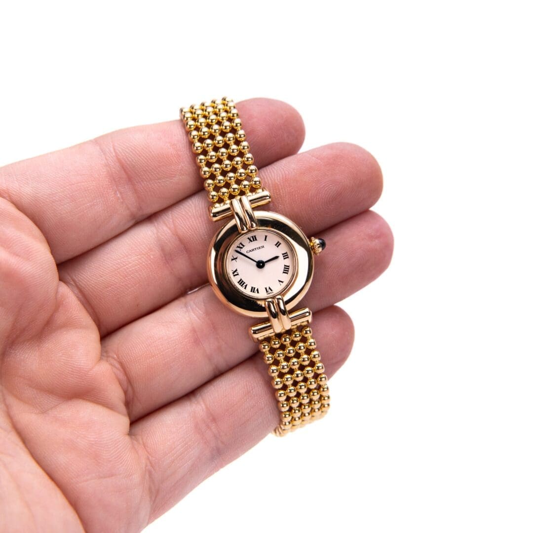 Gold wristwatch with Roman numerals in hand.