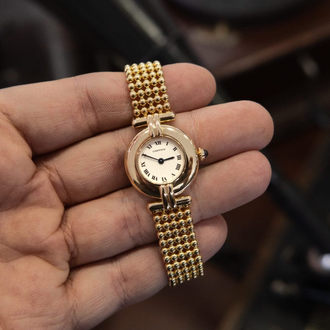 Gold watch with Roman numerals on hand.
