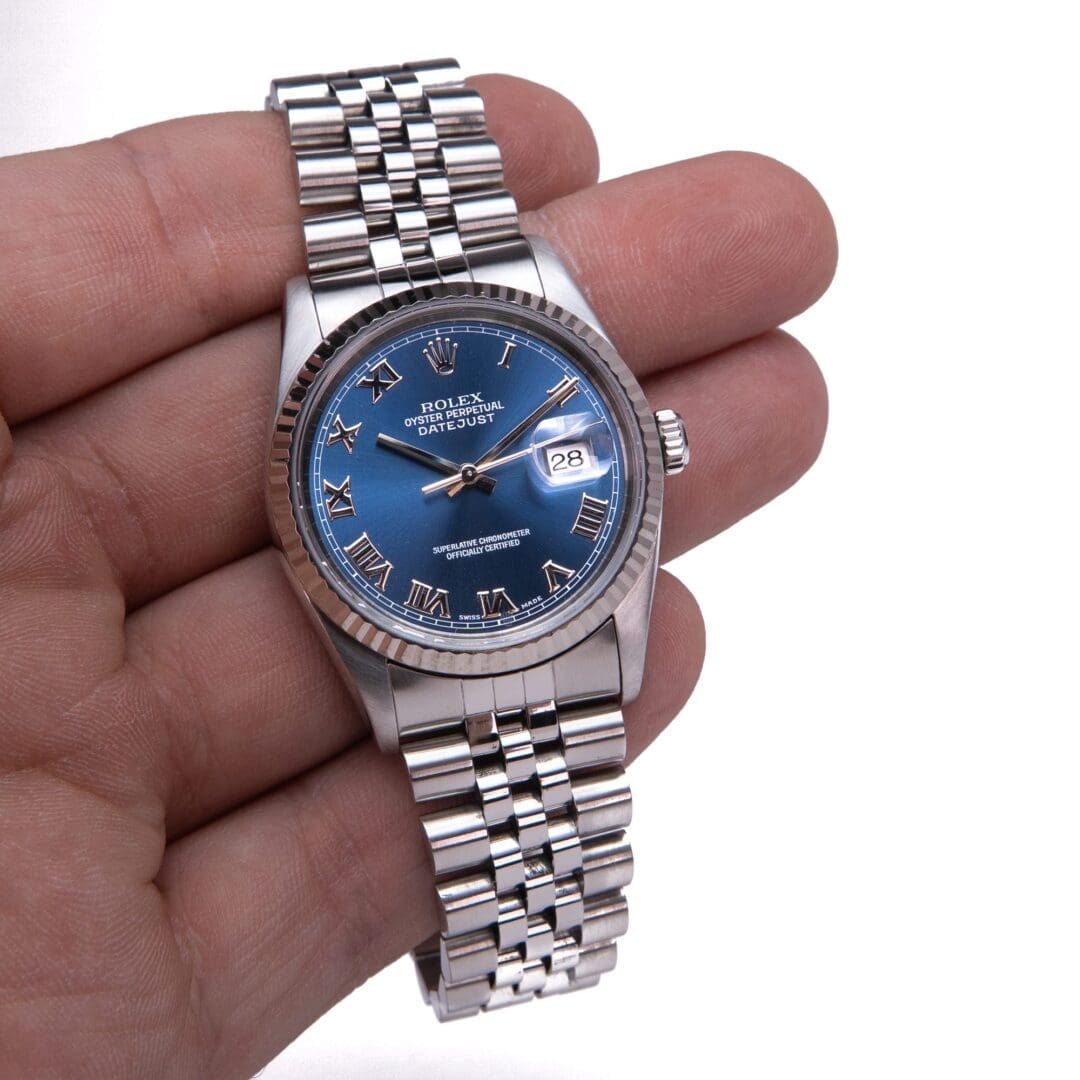 Hand holding a silver Rolex watch.