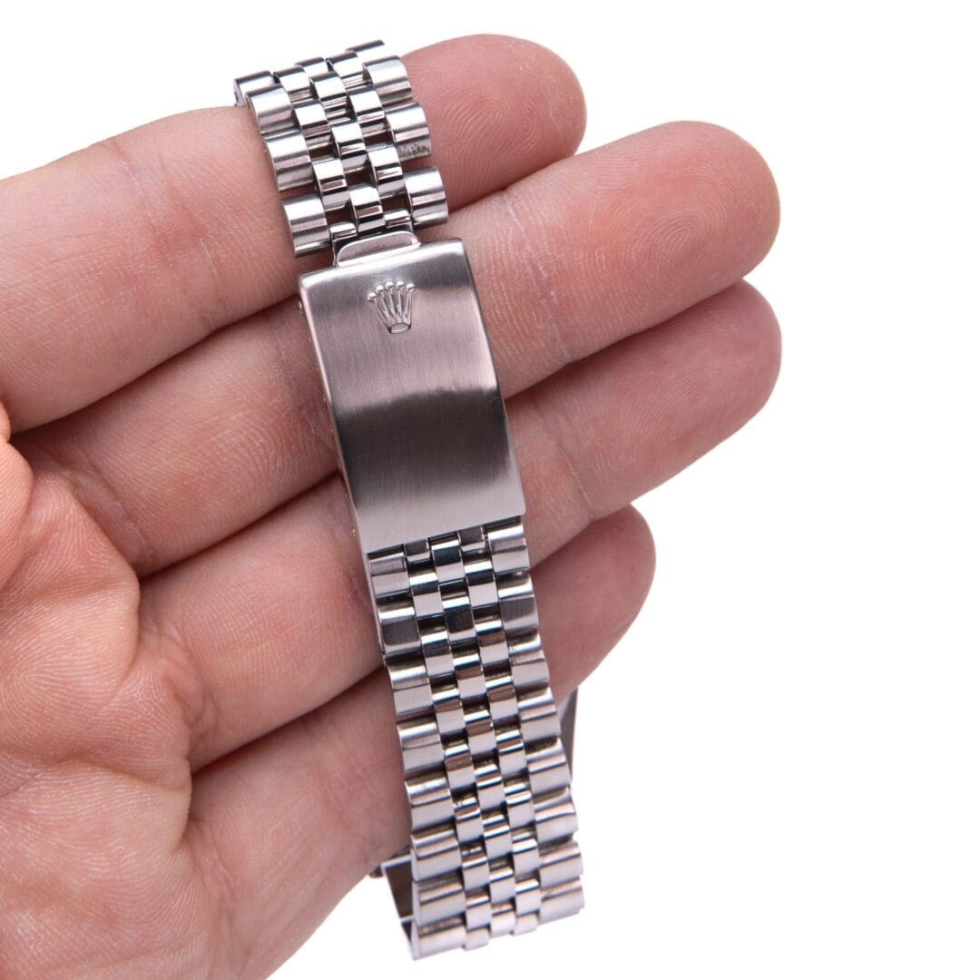 Hand holding a silver watch bracelet clasp.