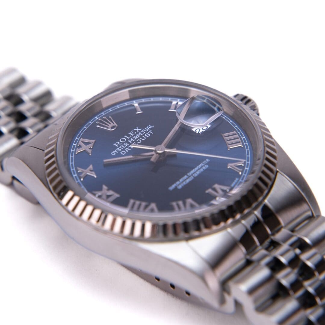 Silver wristwatch with blue dial close-up.