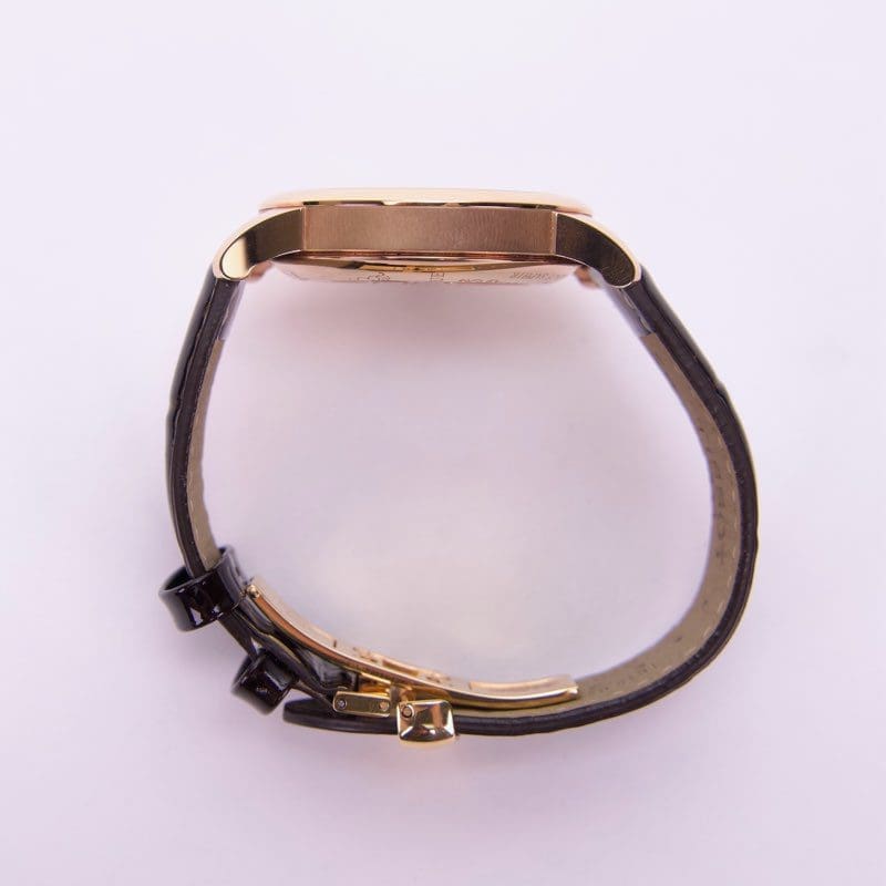 Gold watch with black leather strap.