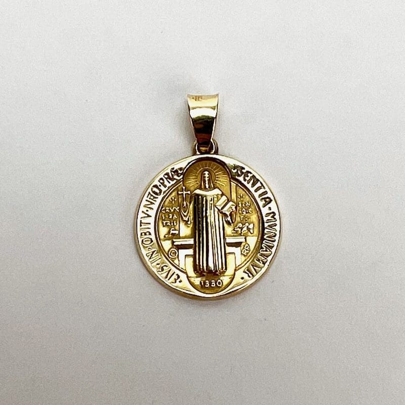 Gold Saint Benedict medallion on white background.