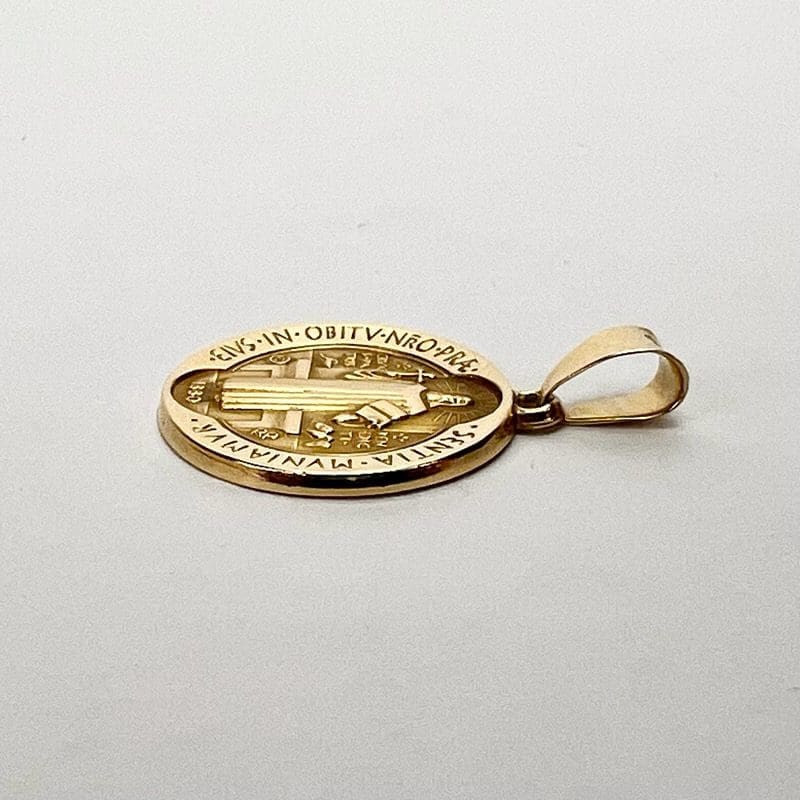 Gold Saint Benedict medal on white background.