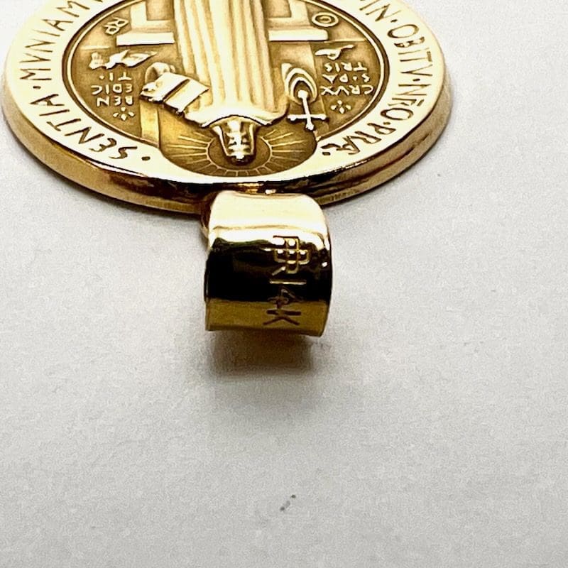 Gold pendant with intricate engraved design.