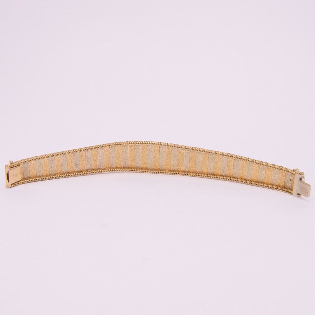 Gold mesh bracelet on white background.