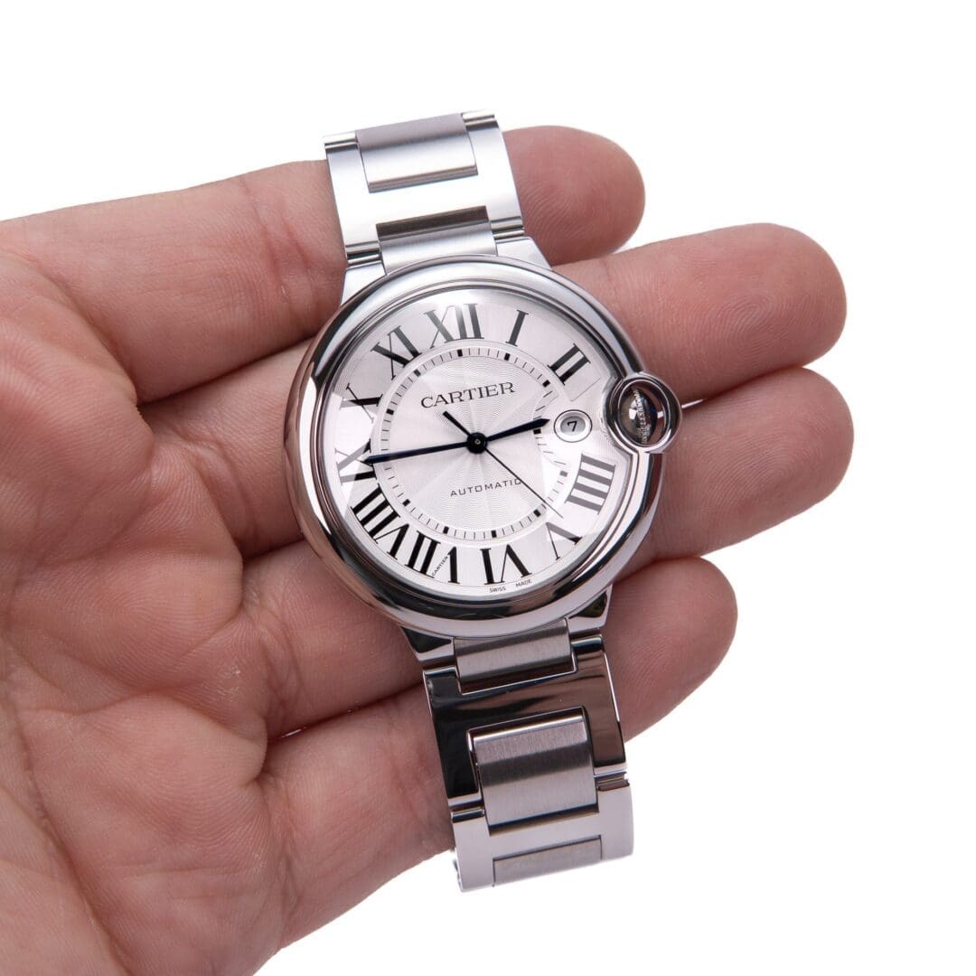 Hand holding a silver wristwatch with numbers.