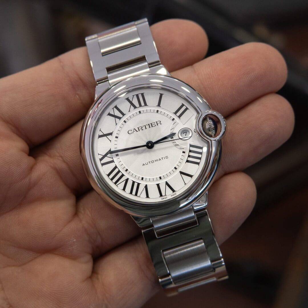 Hand holding a luxury silver wristwatch.
