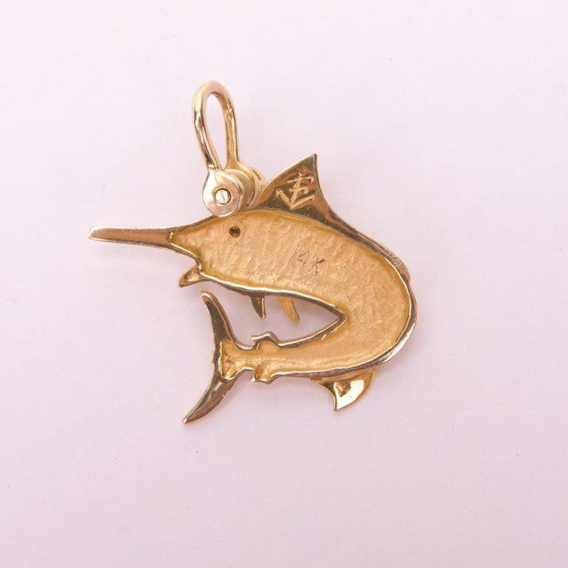Gold fish-shaped pendant on light background.