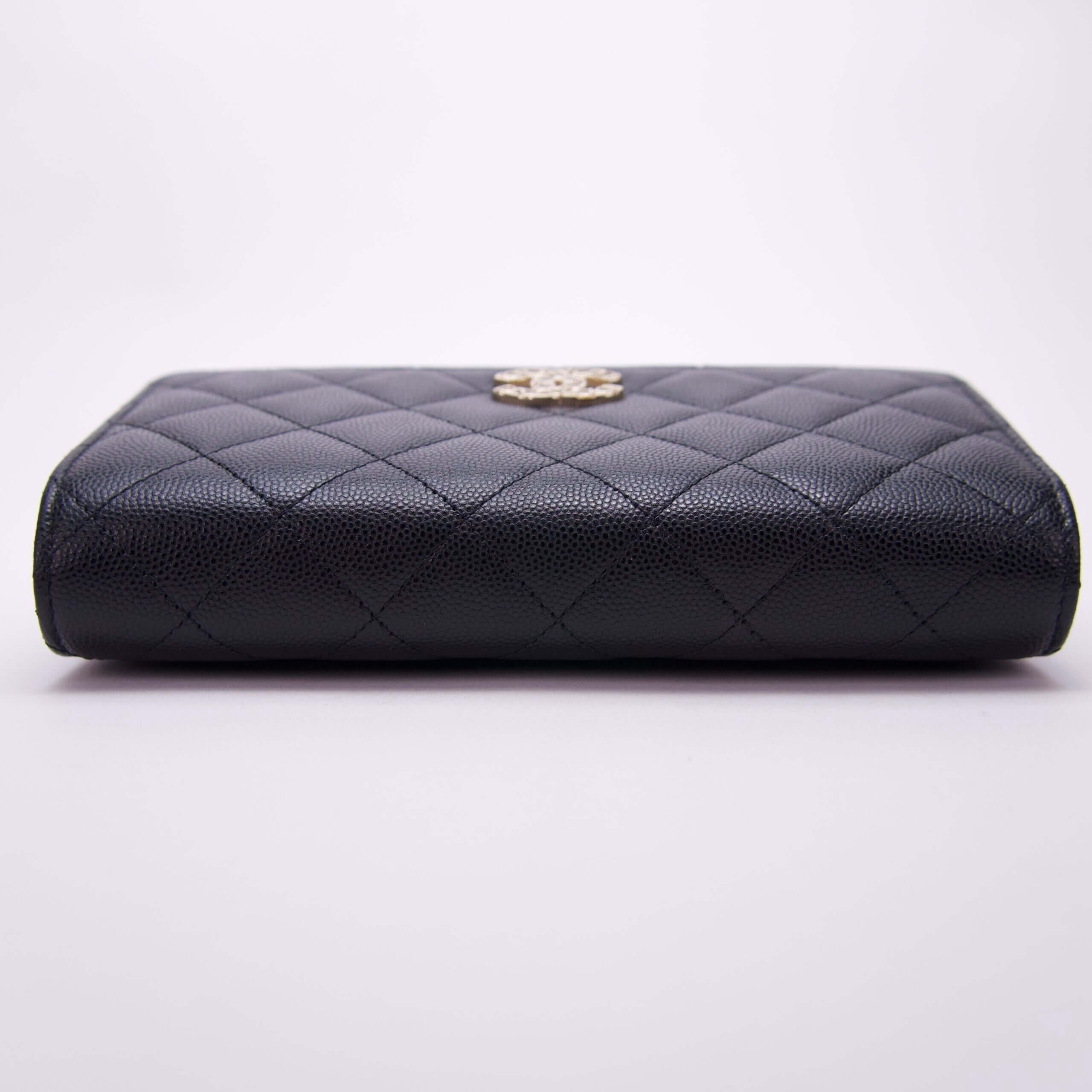 Black quilted leather wallet, gold logo clasp.
