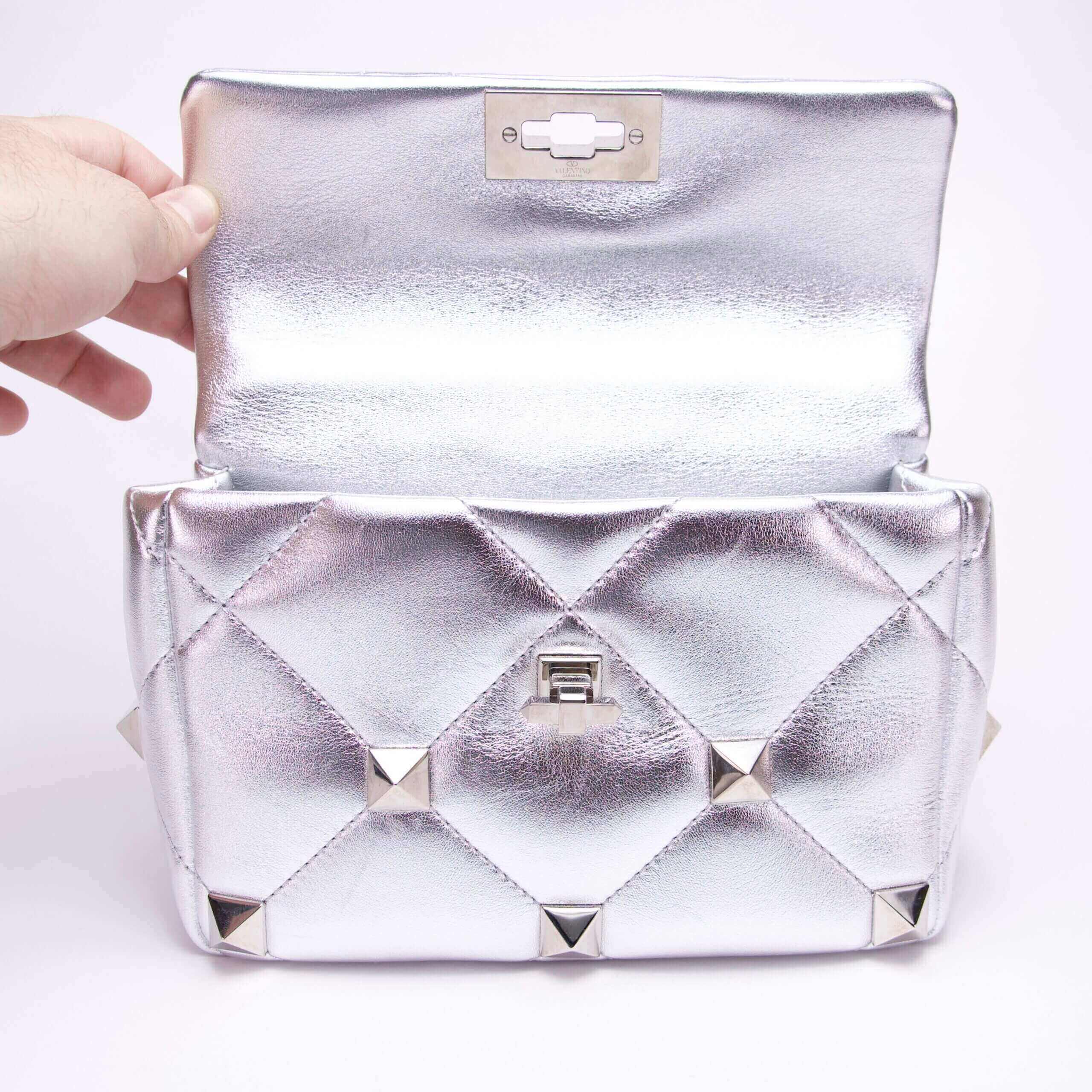Silver quilted handbag with open flap.