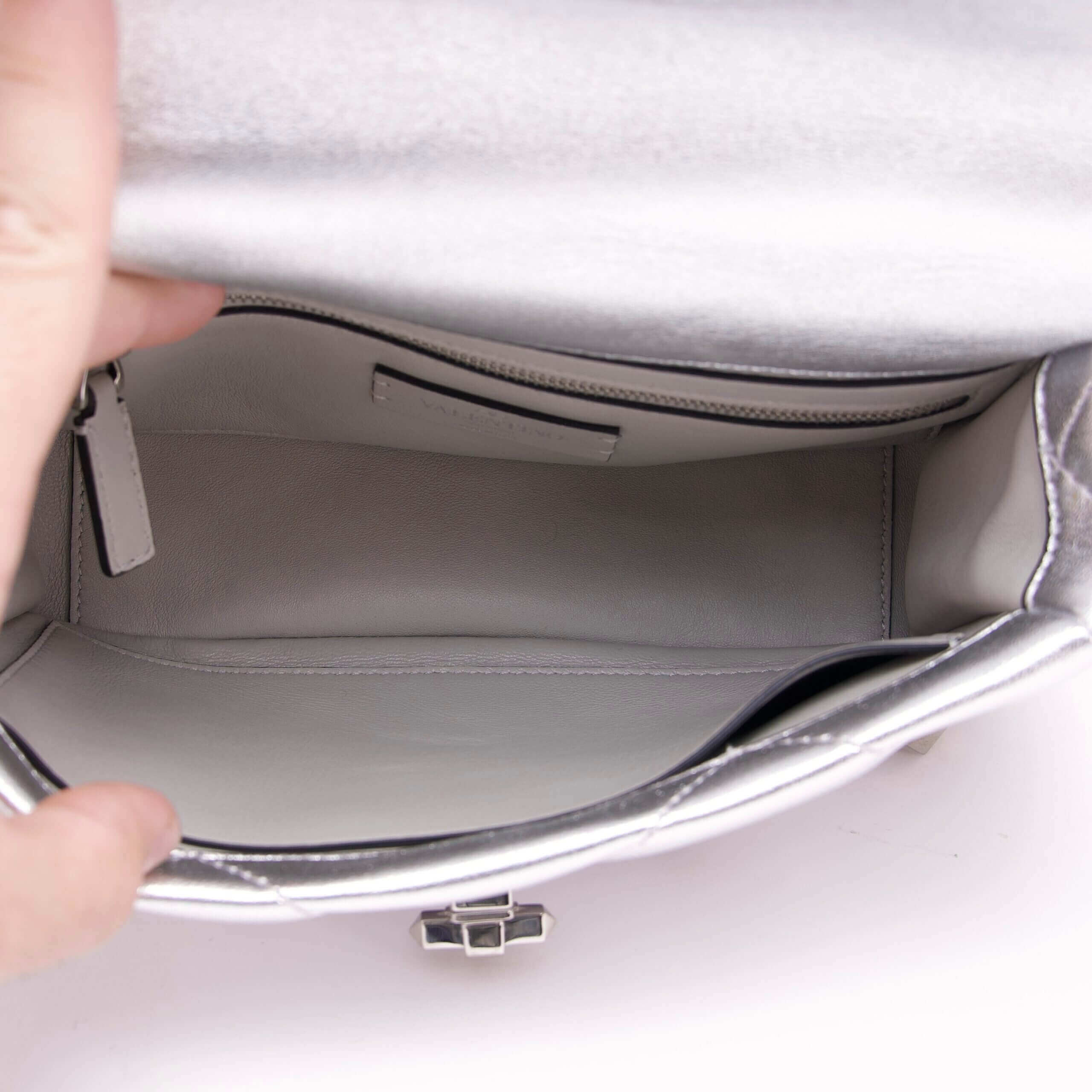 Open silver handbag showing empty interior.