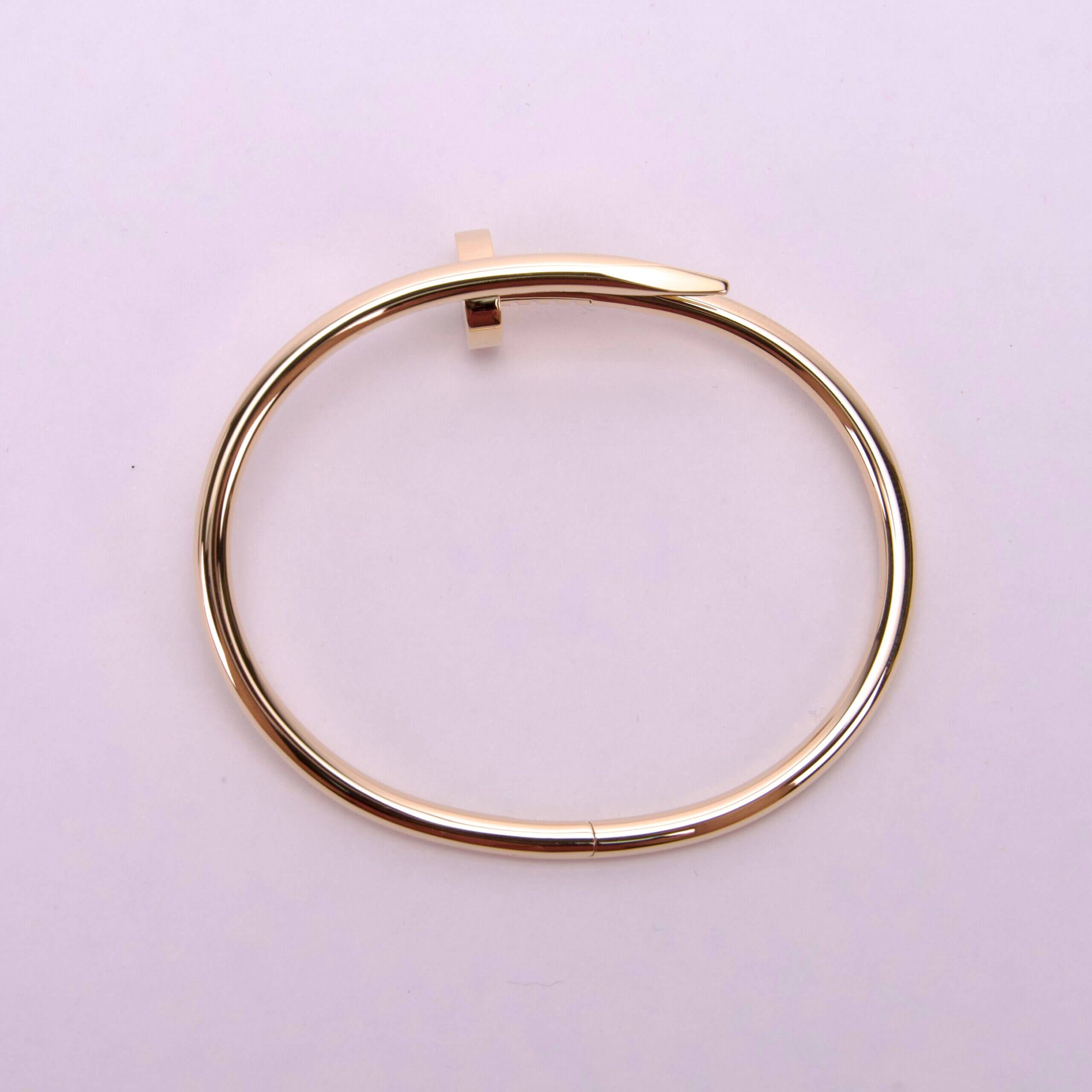 Gold nail-shaped bangle on white background.