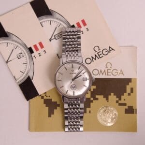 Silver wristwatch with Omega branding and brochures.