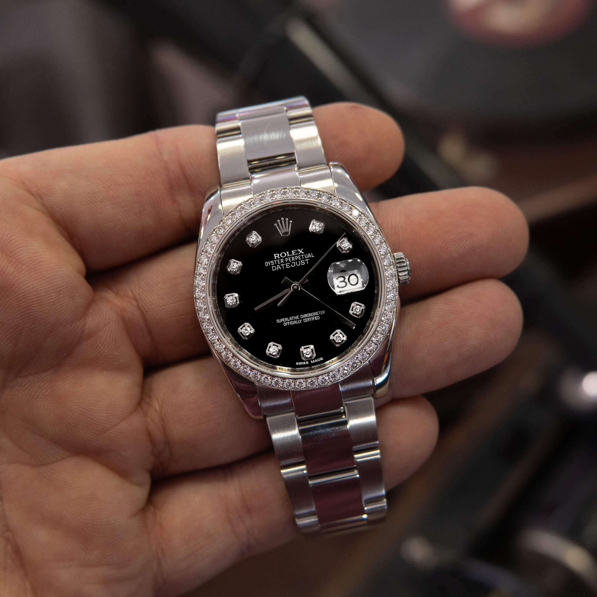 Hand holding a luxury silver wristwatch.