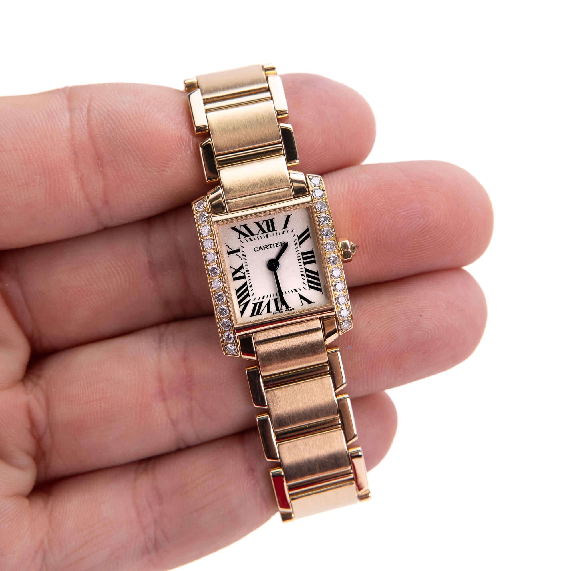 Gold wristwatch with Roman numerals in hand.