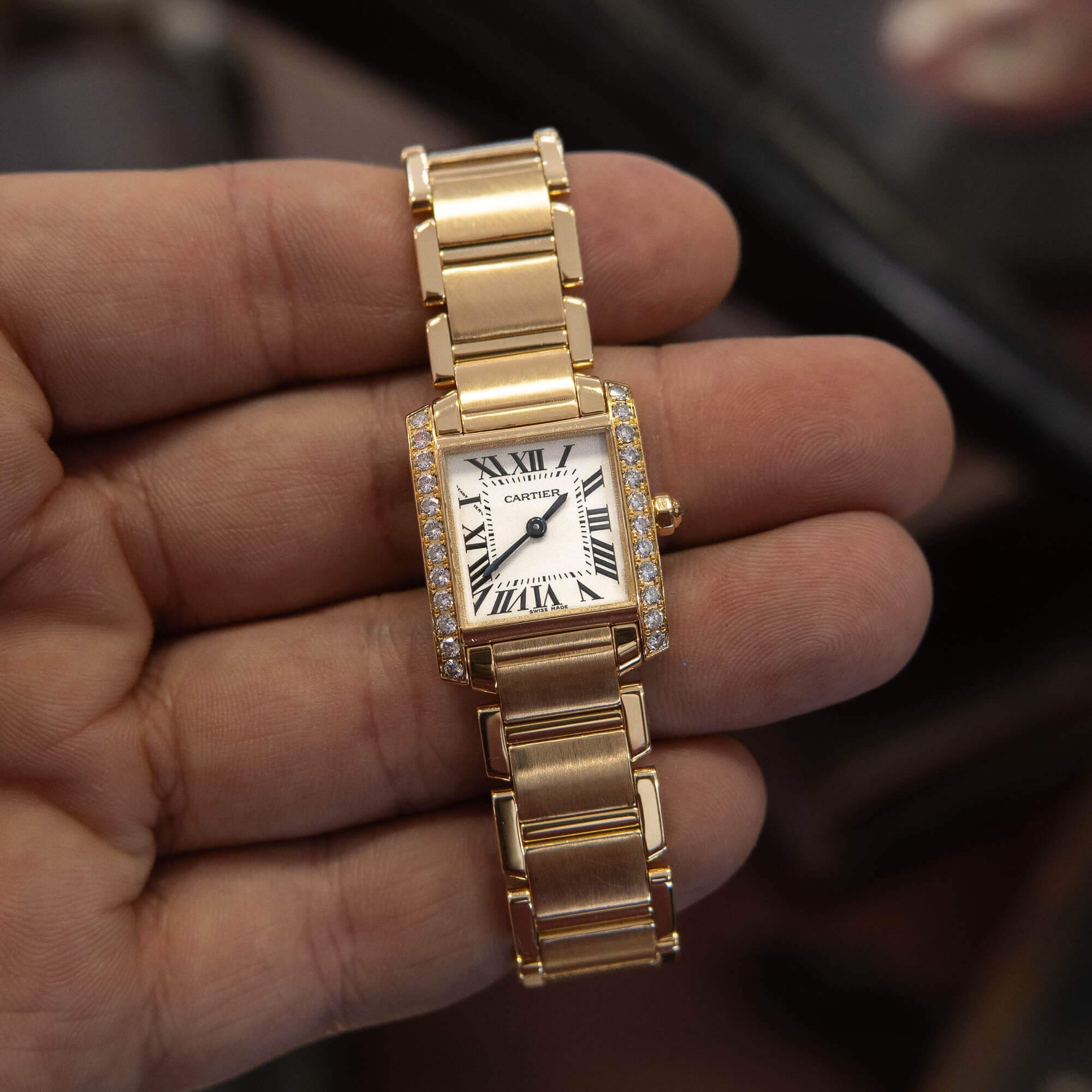 Gold wristwatch with Roman numeral face.