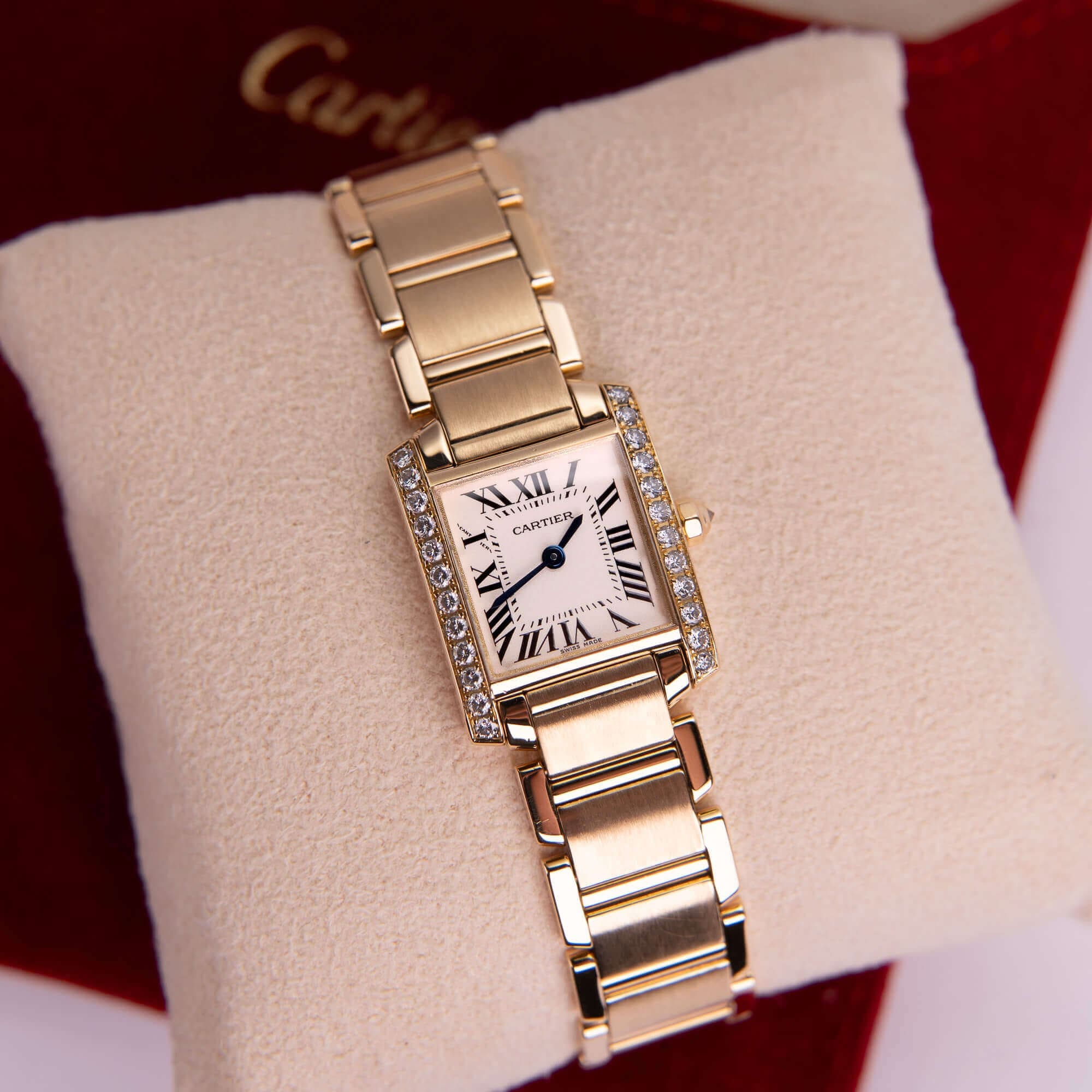 Gold wristwatch with diamond accents displayed.