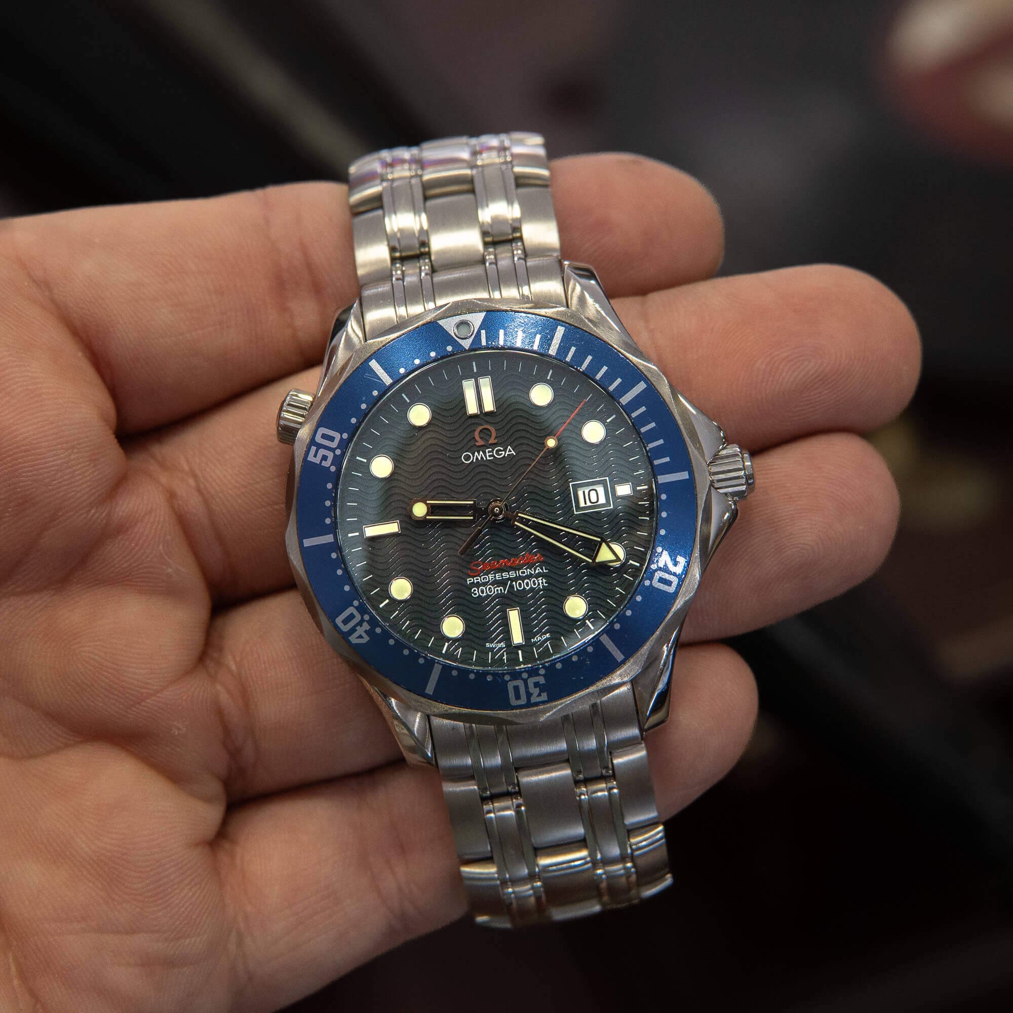 Hand holding a silver and blue watch.