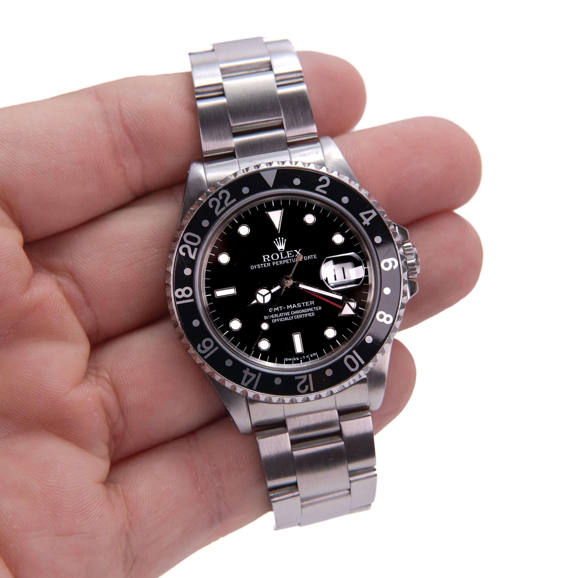 Hand holding a silver wristwatch.
