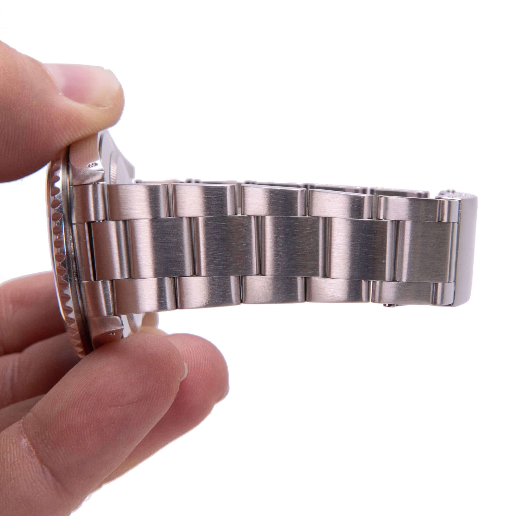Hand holding stainless steel watch bracelet.