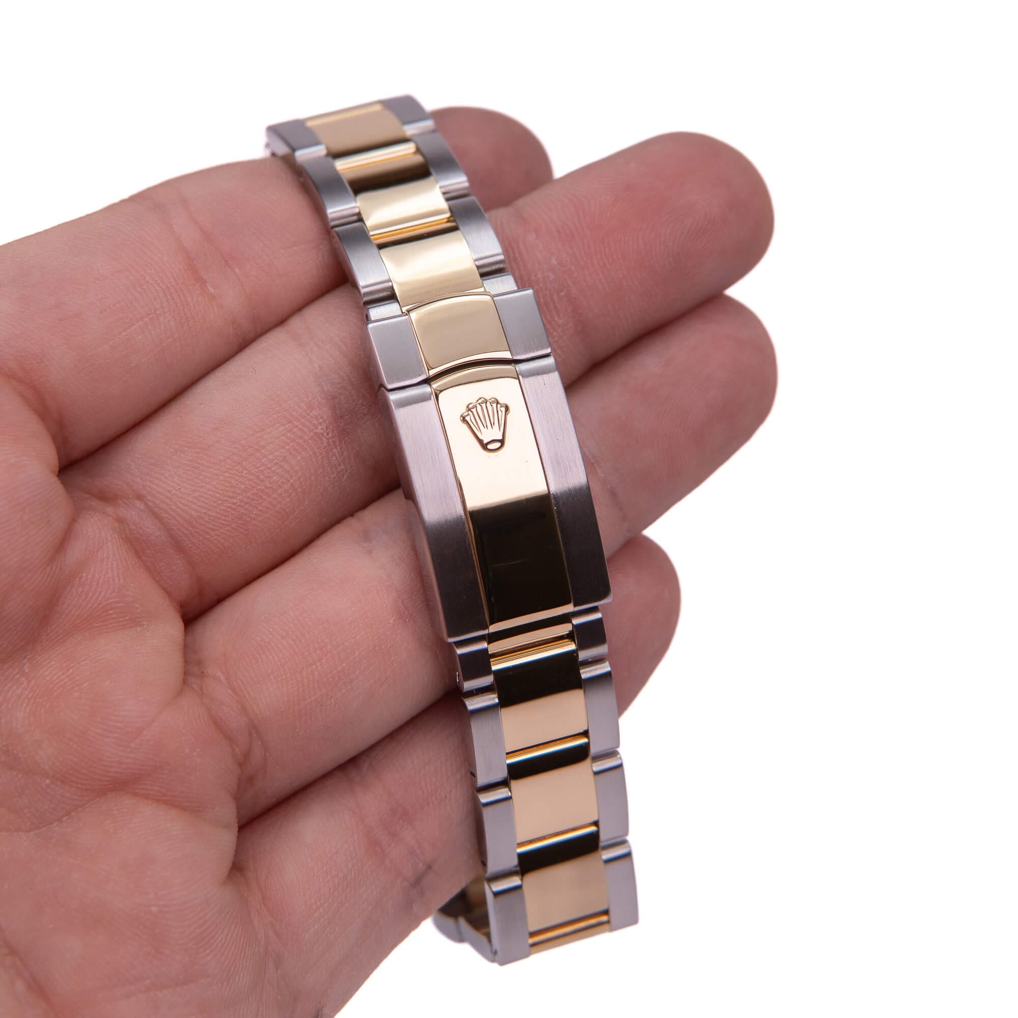 Two-tone watch bracelet held in hand.