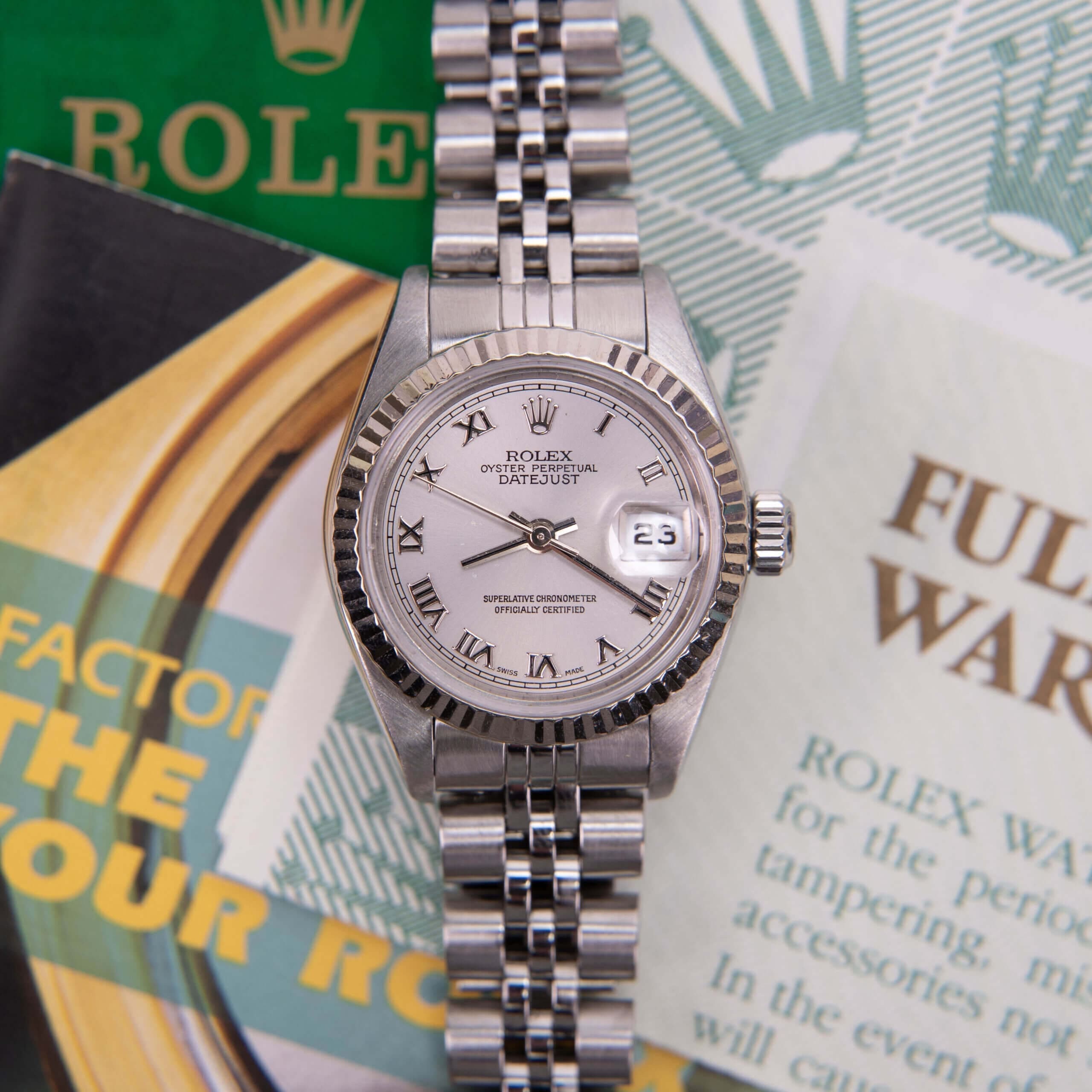Silver Rolex watch on brochures background.