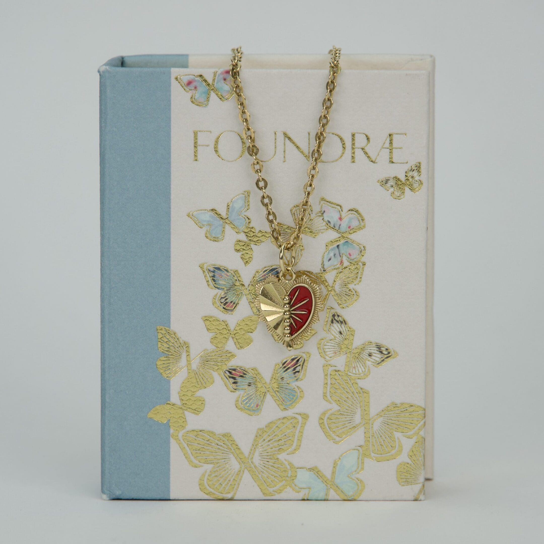 Heart pendant necklace on butterfly-patterned book.