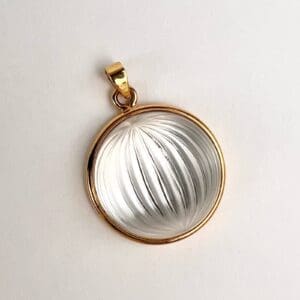 Gold-framed clear pendant with textured design.