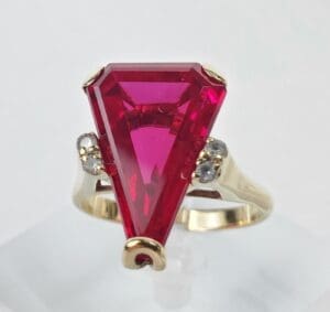 Gold ring with large triangular red gemstone.