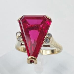 Gold ring with large triangular red gemstone.