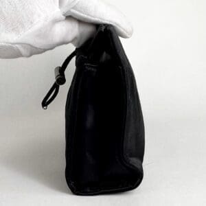 Gloved hand holding small black pouch.