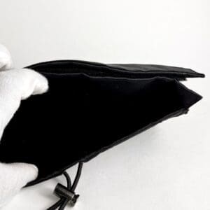 Gloved hand holding empty black wallet.