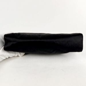 Gloved hand holding a black object.