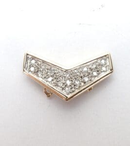 Gold chevron brooch with embedded stones.