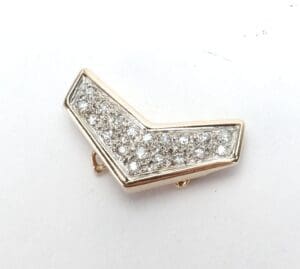 Gold chevron brooch with embedded diamonds.