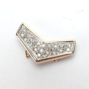 Gold chevron brooch with embedded diamonds.