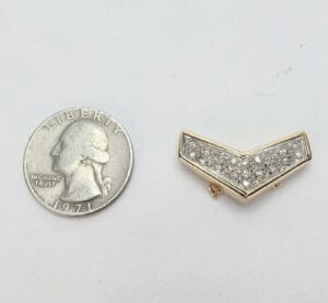 Quarter and diamond-studded gold chevron pin.
